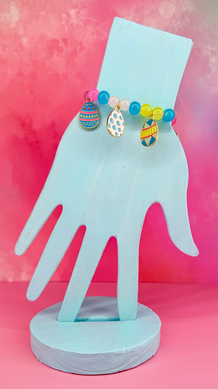Colorful beaded bracelet with three enamel egg charms on display stand