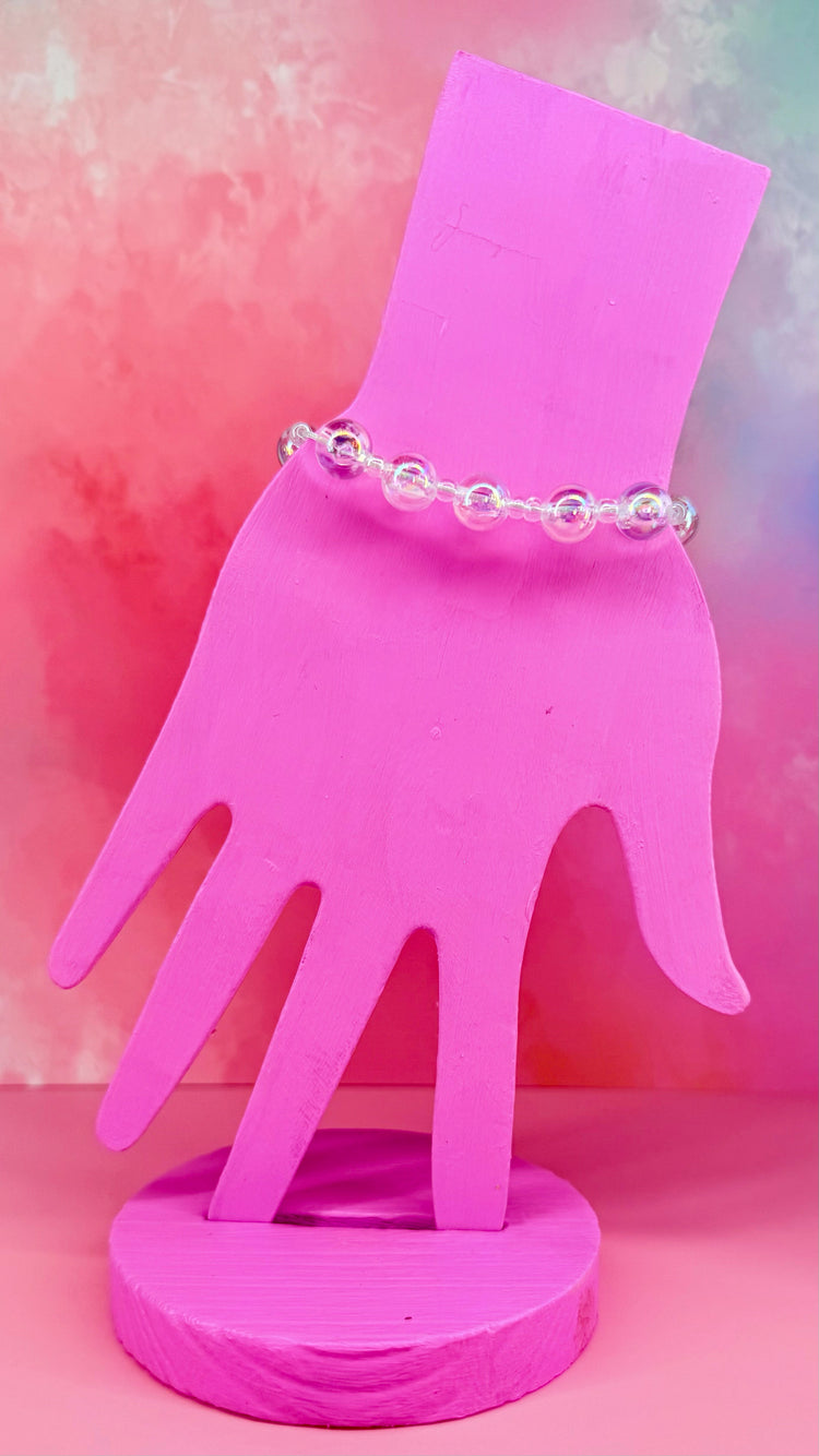 Stack of three pastel and iridescent bracelets on a pink hand display