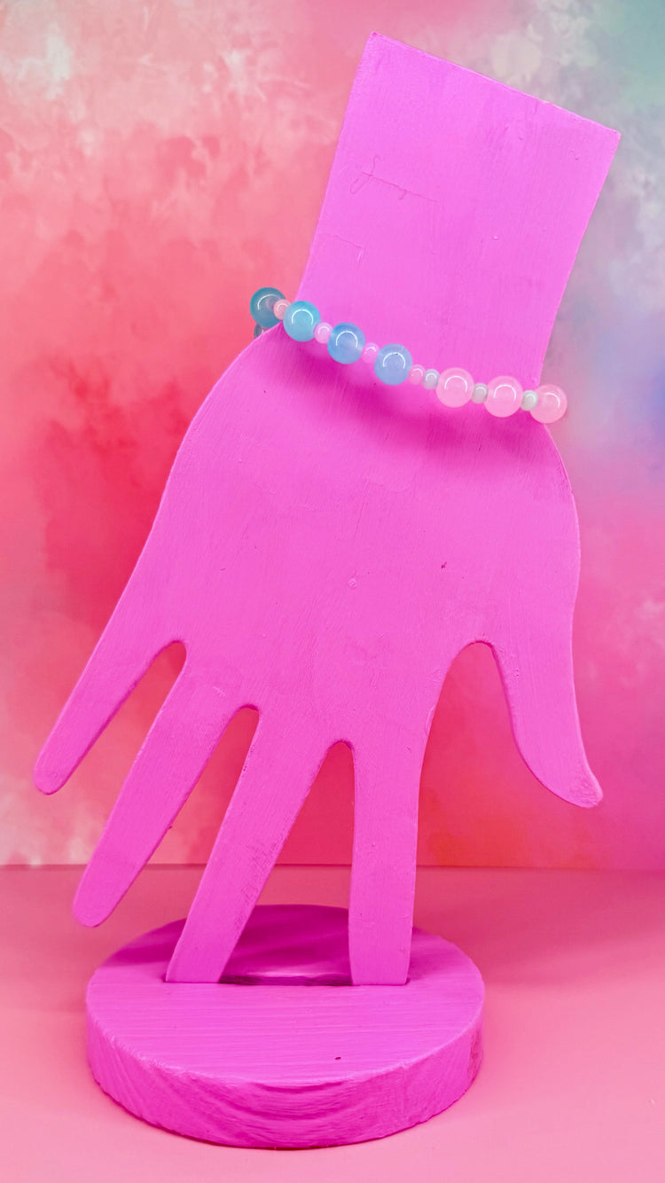 Bracelet with yellow and blue translucent beads on a pink display hand
