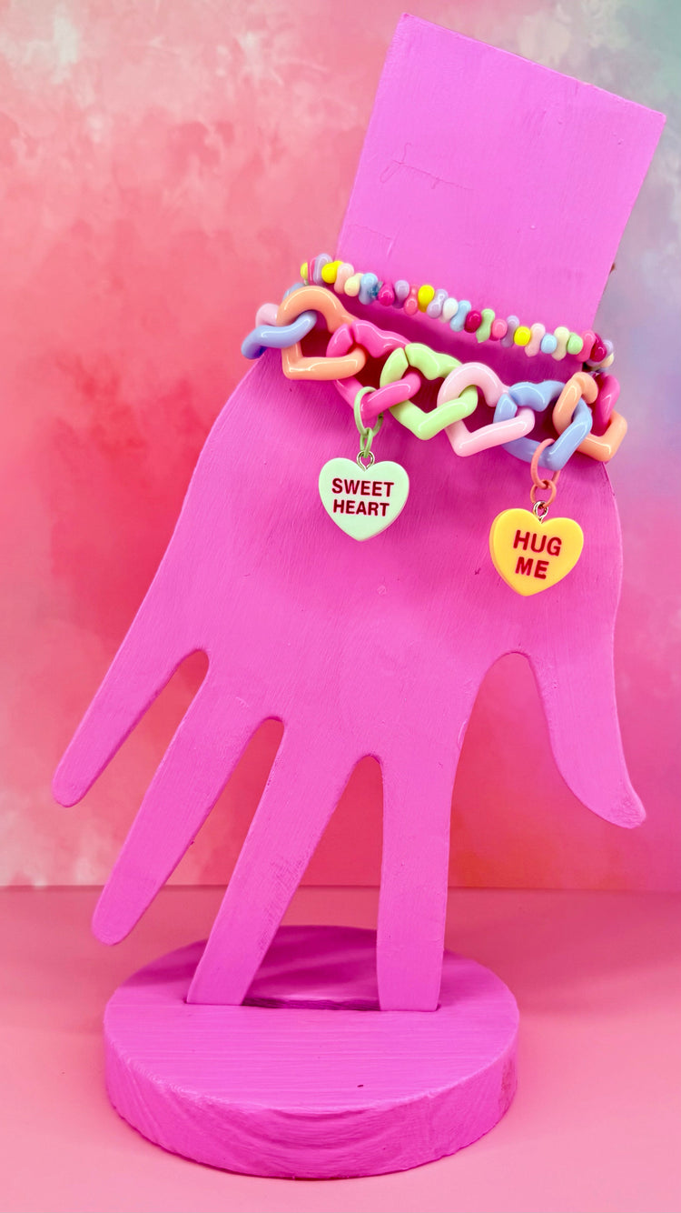 Stack of pastel chain bracelet and beaded jellybean bracelet on pink hand display
