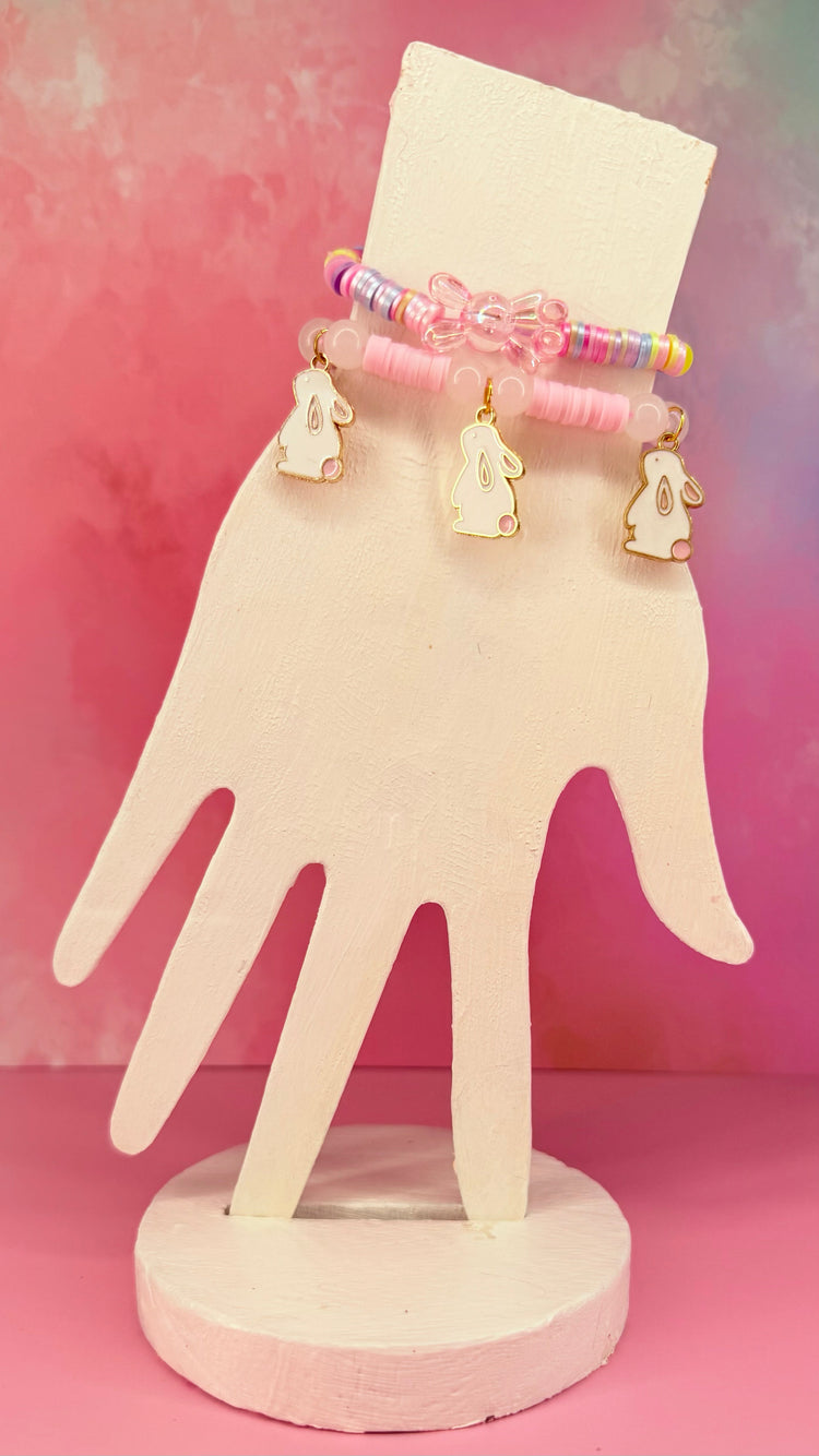 Stacked pink and pastel beaded bracelets with bunny charms