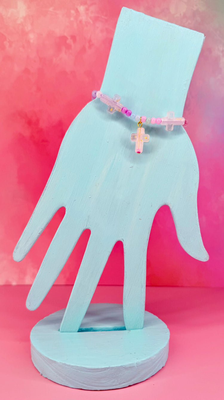 Pastel beaded bracelet with iridescent cross charms on display