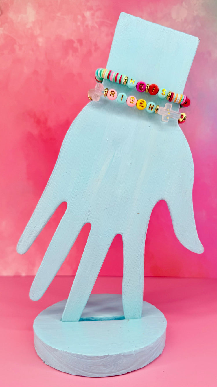 Colorful two-bracelet set with 'He Is Risen' lettering and cross charms