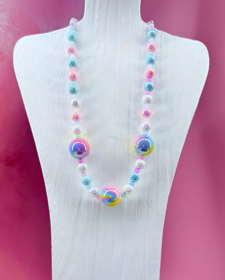 Necklace with large iridescent pastel beads on display stand with pink background