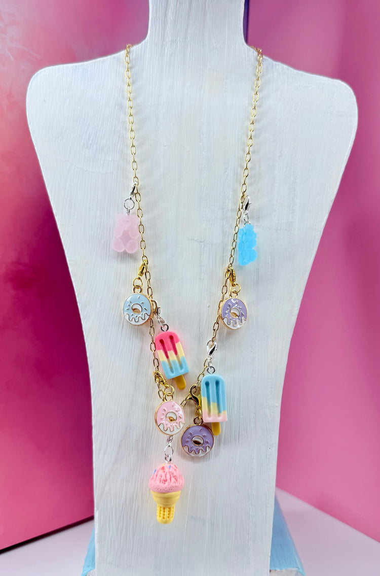 Necklace with candy-themed charms on gold chain displayed on bust