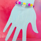 Beaded bracelet with clear bunny-shaped charm on pastel background