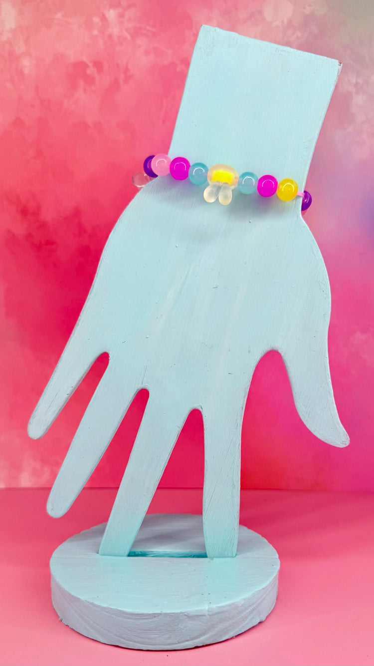 Beaded bracelet with clear bunny-shaped charm on pastel background