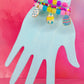 Stacked pastel bead bracelets with colorful egg charms on blue hand display