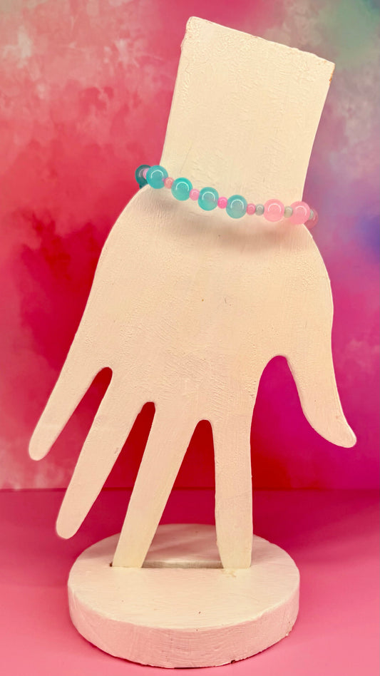 Bead bracelet with yellow and blue tones displayed on a pink hand