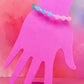 Bracelet with yellow and blue translucent beads on a pink display hand