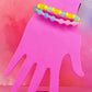 Stacked pastel bracelets on a pink hand display with multicolored beads