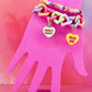 Stack of pastel chain bracelet and beaded jellybean bracelet on pink hand display