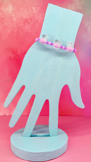 Pink beaded bracelet with three translucent bunny shapes on display