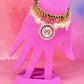 Gold beaded charm bracelet with bow medallion on a pink hand display