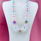 Necklace with large iridescent pastel beads on display stand with pink background